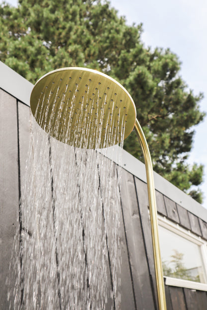 Brass Gardentub Shower with running water against a dark timber wall
